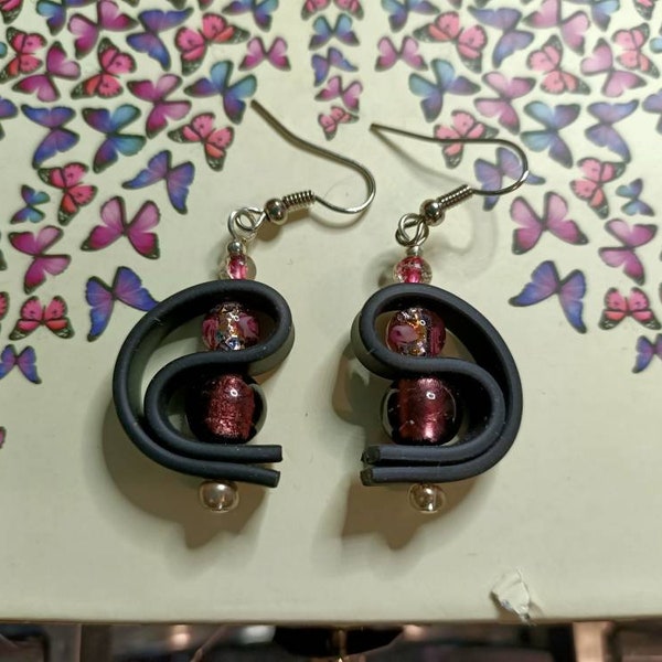 Boucles d'oreilles originales et modernes en buna cord souple noir entourant de jolies perles de verre dans les tons prunes et roses.