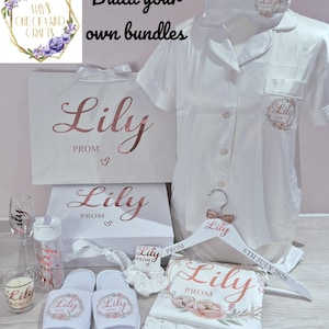 May include: A white pyjama set with a short-sleeved button-down shirt, matching sleep mask, and slippers, all personalised with the name Lily and floral accents. Includes a gift bag, box, water bottle, wine glass, candle, and a hanger with the text Lily Prom 6th July 2026.