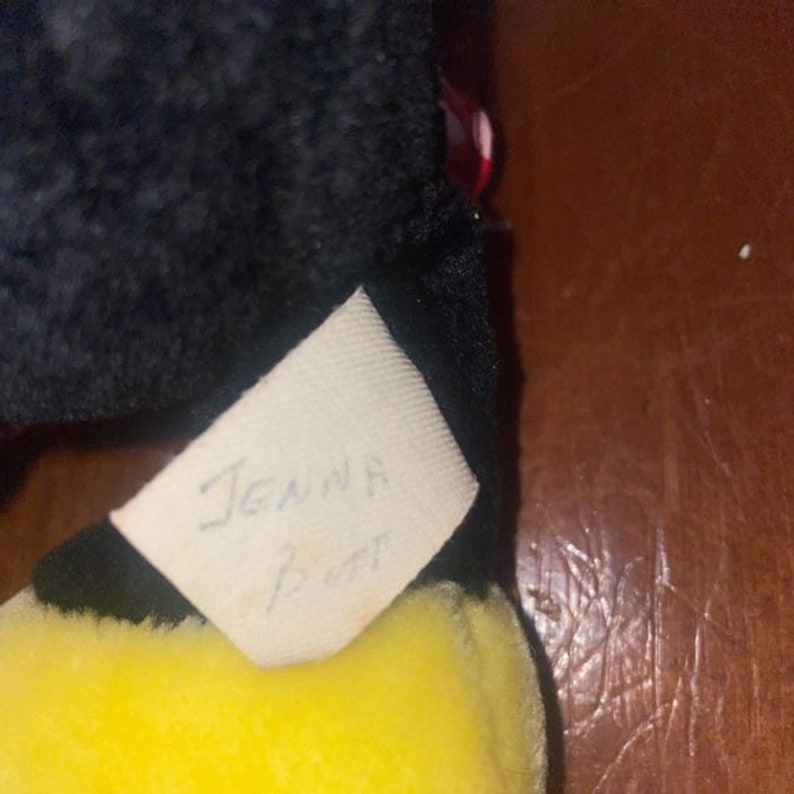 May include: A black and yellow plush toy with a white tag that says "Jenna 1997".