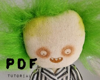May include: PDF tutorial and pattern for making a green-haired doll with a striped suit. The doll has a stitched-on face with a toothy grin.