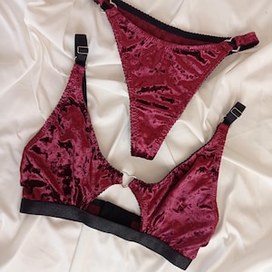May include: A burgundy velvet lingerie set with a heart-shaped ring detail. The set includes a bra and a thong.