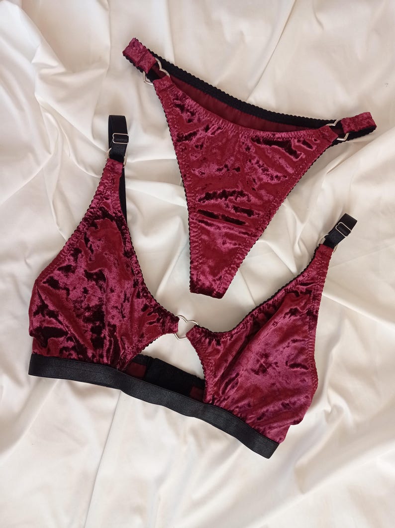 May include: A burgundy velvet lingerie set with a heart-shaped ring detail. The set includes a bra and a thong.