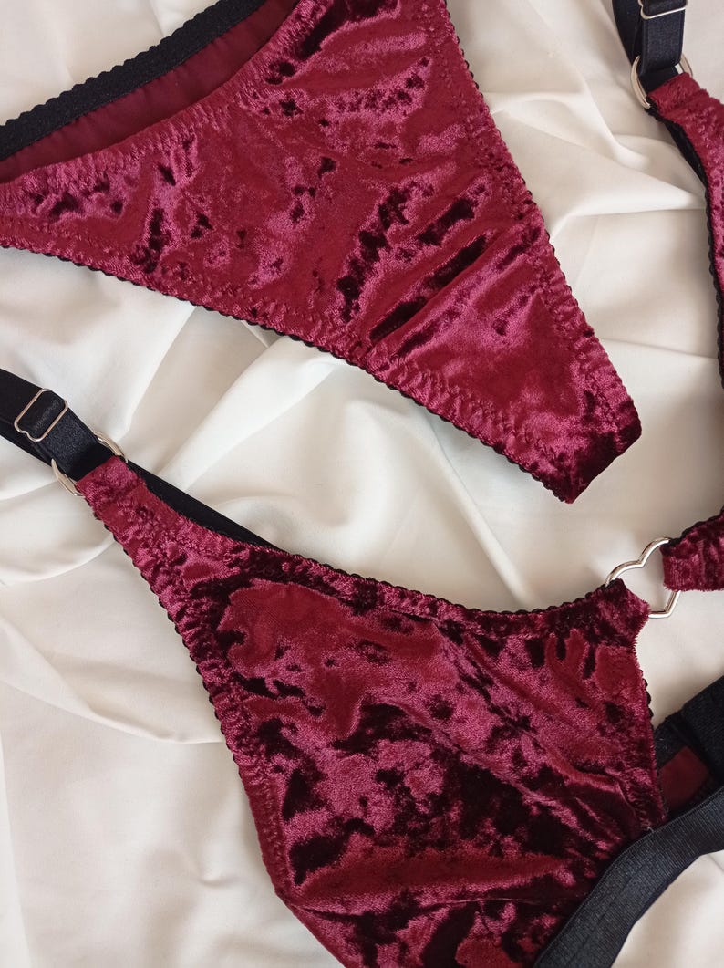 May include: A burgundy velvet lingerie set with black straps and a heart-shaped ring detail.