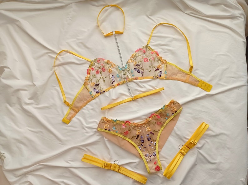 May include: A yellow floral embroidered lingerie set with a matching choker. The set includes a bra and panty with delicate lace trim.