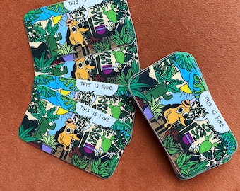 May include: A set of four illustrated cards featuring a cartoon dog with the text "This is fine." The cards are printed on a white background with green, blue, and yellow accents.