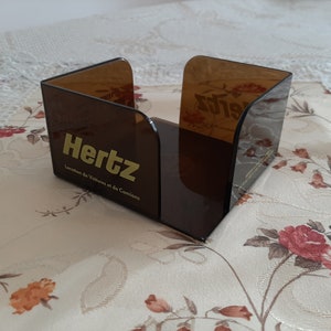 Puede incluir: Un organizador de escritorio de plástico marrón con el logotipo de Hertz y el texto "Location de Voitures et de Camions".