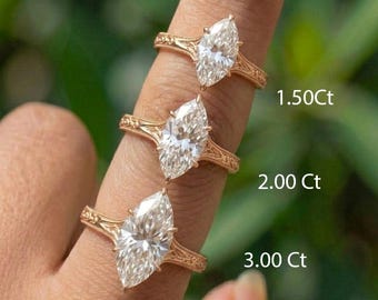 Pode incluir: Três anéis de ouro com diamantes em corte marquise são exibidos. Os anéis estão em um dedo, com os tamanhos dos diamantes rotulados como 1,50 Ct, 2,00 Ct e 3,00 Ct. Os anéis têm um design de banda ornamentado.