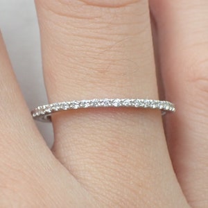 May include: A thin silver band with a row of small diamonds set in a pave setting.
