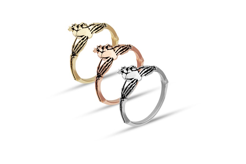 Puede incluir: Tres anillos de Claddagh en oro, oro rosa y plata. Cada anillo presenta un coraz&oacute;n sostenido por dos manos, coronado por una corona. Los anillos se exhiben sobre un fondo blanco, mostrando su intrincado dise&ntilde;o y acabados met&aacute;licos.