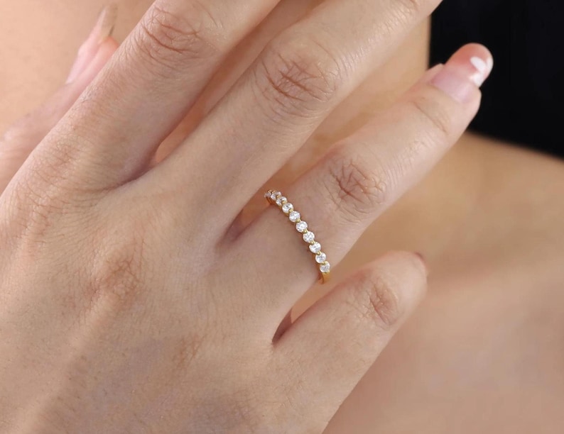 May include: A gold band ring with a row of small, clear cubic zirconia stones.