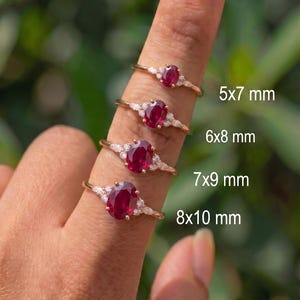 Puede incluir: Cuatro anillos de oro con rubíes rojos de corte ovalado y pequeñas piedras blancas. Los anillos están etiquetados con los tamaños 5x7 mm, 6x8 mm, 7x9 mm y 8x10 mm, indicando las dimensiones de los rubíes centrales de cada joya.