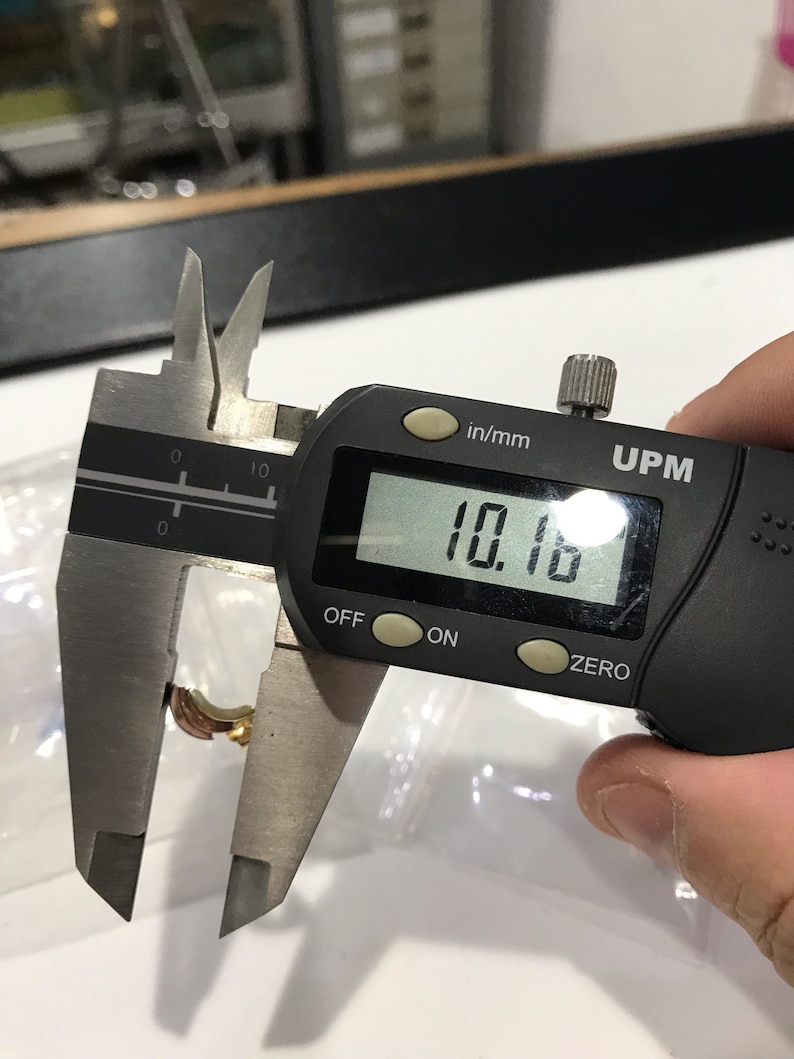 May include: A black digital caliper measuring 10.16 inches. The caliper has a black display with white numbers, and the words "in/mm" and "UPM" are printed on the display.