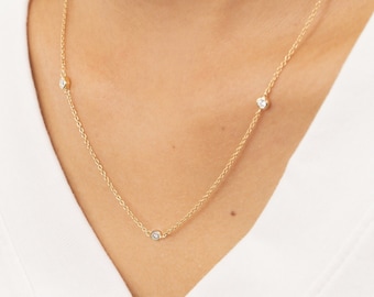 May include: A delicate gold chain necklace with three small round diamonds.