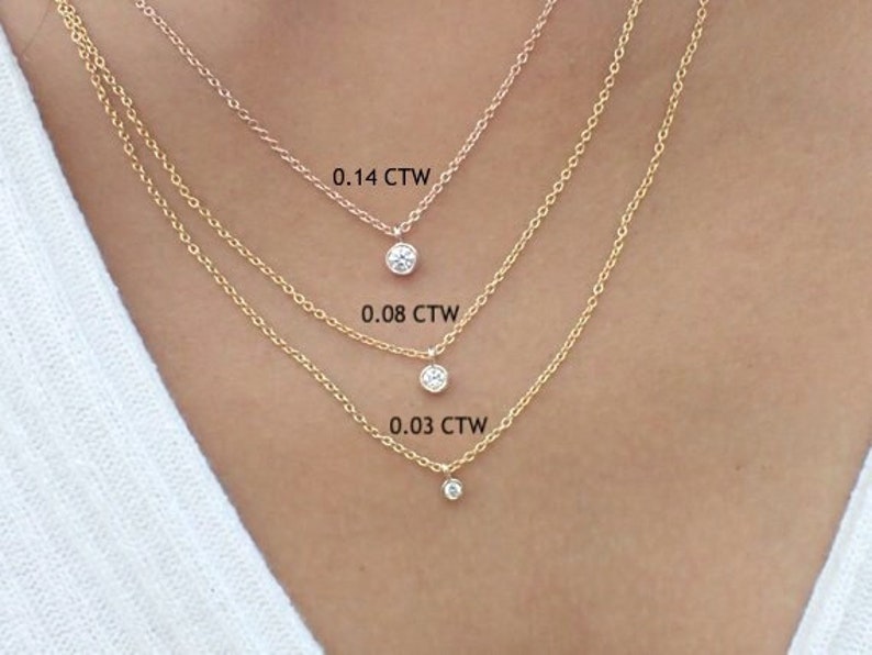 May include: Three gold necklaces with different sized diamond pendants. The pendants are labeled with their carat weight: 0.14 CTW, 0.08 CTW, and 0.03 CTW.