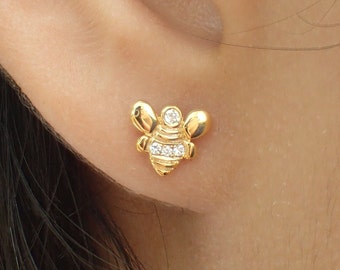 Op de afbeelding: Gouden bijen oorbel studs met heldere zirkonia stenen. De bij is gedetailleerd met een textuur lichaam en vleugels.