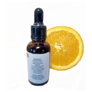 Puede incluir: Una botella de vidrio marr&oacute;n con un cuentagotas negro y una etiqueta blanca, junto a una rodaja de naranja. La etiqueta enumera ingredientes como agua destilada y &aacute;cido L-asc&oacute;rbico. La botella es solo para uso externo.