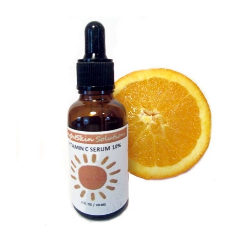 May include: A brown glass bottle of Vitamin C Serum 10% with a black dropper, next to a sliced orange. The label features a sun graphic and the text "BrightSkin Solutions". The bottle contains 1 fl oz / 30 ml of serum.
