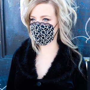 Może przedstawiać: Kobieta z blond włosami w czarnej aksamitnej kurtce z kołnierzem z futra i czarno-białą maską na twarz.