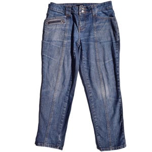 Puede incluir: Un par de pantalones vaqueros azules con un bolsillo con cremallera en el lado izquierdo. Los pantalones tienen una pierna recta y una bragueta con botones.