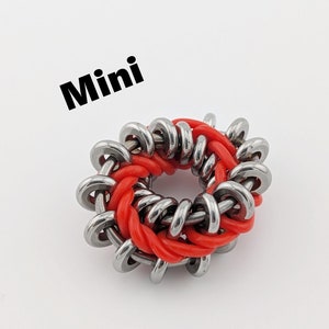 May include: A red and silver mini fidget toy in the shape of a ring. The toy is made of metal and rubber.