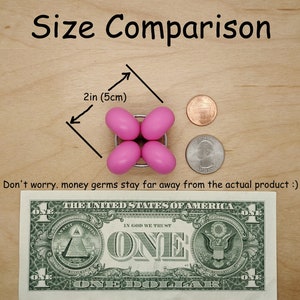 Puede incluir: Comparaci&oacute;n de tama&ntilde;o de un juguete fidget de silicona rosa con un billete de un d&oacute;lar estadounidense. El juguete tiene un di&aacute;metro de 5 cm (2 pulgadas).