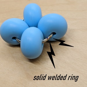 Puede incluir: Un juguete antiestr&eacute;s de silicona azul con cuatro esferas conectadas por un anillo met&aacute;lico soldado.