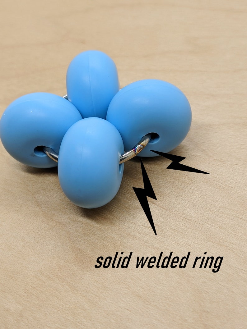 Puede incluir: Un juguete antiestr&eacute;s de silicona azul con cuatro esferas conectadas por un anillo met&aacute;lico soldado.