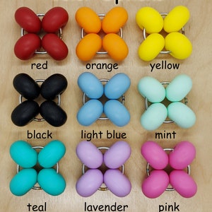 Puede incluir: Opciones de color para un juguete sensorial de silicona. El juguete tiene forma de estrella de cuatro puntas con bordes redondeados. Los colores son rojo, naranja, amarillo, negro, azul claro, menta, turquesa, lavanda y rosa.