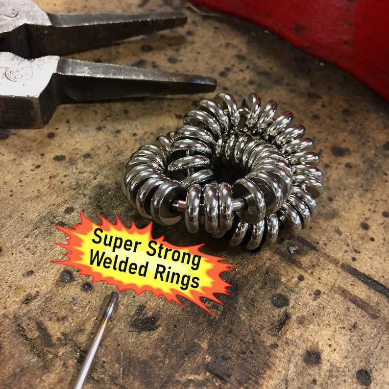 Puede incluir: Un conjunto de anillos soldados plateados brillantes, dispuestos en espiral, con el texto "Super Strong Welded Rings" en un gr&aacute;fico amarillo y rojo en forma de explosi&oacute;n. Se ven unos alicates en el fondo.