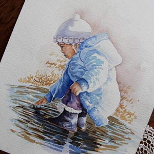 May include: Watercolor painting of a child wearing a blue coat and white hat, standing in a puddle of water. The child is reaching out with their hand to touch the water. The painting is signed "Twila Green".