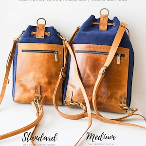 May include: Two convertible leather and canvas backpacks in blue and brown. The backpack on the left is labeled 'Standard' and has one front zipper pocket and a 1.5cm leather strap. The backpack on the right is labeled 'Medium' and has one front pocket and a bottom zipper pocket with a 2cm leather strap. Both backpacks have double stitched straps.