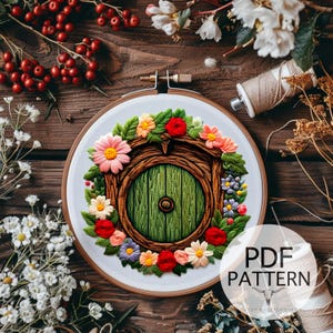 Può includere: Ricamo su telaio raffigurante una porta verde rotonda, circondata da una ghirlanda di fiori colorati. Il disegno è su sfondo bianco all'interno di un telaio di legno. Il testo "PDF PATTERN" è visibile. Tema: artigianato fantasioso.