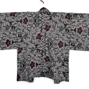 Puede incluir: Un kimono de patrón gris y negro con diseños florales burdeos. El kimono tiene un estilo japonés tradicional.