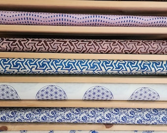 Puede incluir: Una colección de rollos de papel estampados en un estante de madera. Los rollos muestran varios diseños, incluyendo puntos, formas geométricas y patrones florales. Los colores incluyen marrón, azul y blanco. Los rollos de papel están bien organizados y listos para usar.