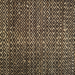May include: Close-up of a woven textile with a repeating diamond pattern. The fabric features a natural beige and dark brown color scheme, creating a textured, geometric design. The weave appears to be tightly constructed, suggesting durability.