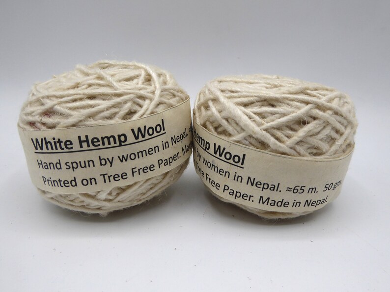 Peut inclure: Deux pelotes de fil de laine de chanvre blanc. Chaque pelote porte une &eacute;tiquette indiquant "White Hemp Wool" et "Hand spun by women in Nepal." Le fil mesure environ 65 m&egrave;tres et p&egrave;se 50 grammes.