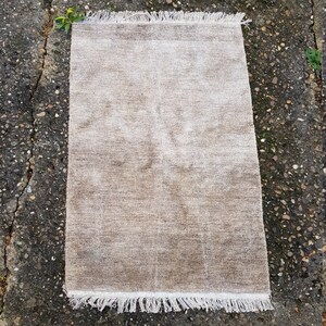 Op de afbeelding: Een rechthoekig, beige tapijt met een getextureerd oppervlak en witte franjes langs de korte uiteinden. Het tapijt heeft een neutraal kleurenpalet, waardoor het geschikt is voor diverse interieurstijlen. De afmetingen van het tapijt zijn niet zichtbaar.