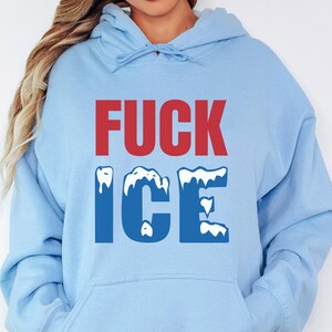 May include: A light blue hoodie with the words "FUCK ICE" printed on the front. The word "FUCK" is in red, and "ICE" is in blue with a snowy design.