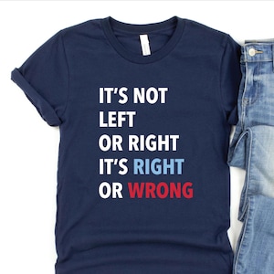 以下が含まれることがあります： 紺色のTシャツに「It's not left or right it's right or wrong」という文字が白でプリントされています。 「right」と「wrong」の文字はそれぞれ青と赤でプリントされています。