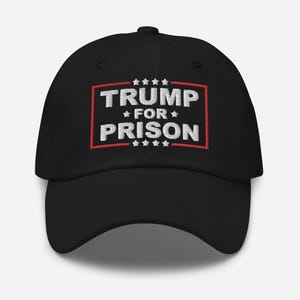 May include: Black baseball cap with red and white embroidered text that reads "TRUMP FOR PRISON" with stars above and below the text.