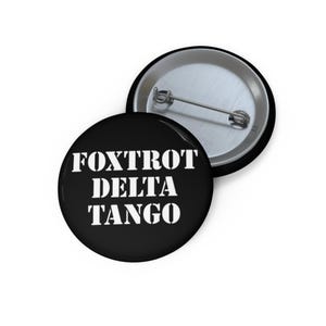May include: Black button with white text that reads "FOXTROT DELTA TANGO".