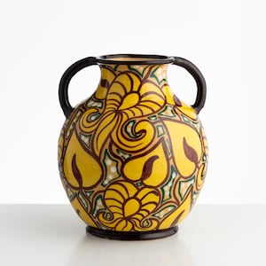 Può includere: Un vaso in ceramica con due manici marrone scuro e un corpo arrotondato. La superficie presenta uno sfondo giallo vivace decorato con un motivo ripetitivo di foglie stilizzate a forma di cuore in marrone scuro e verde, con puntini bianchi.