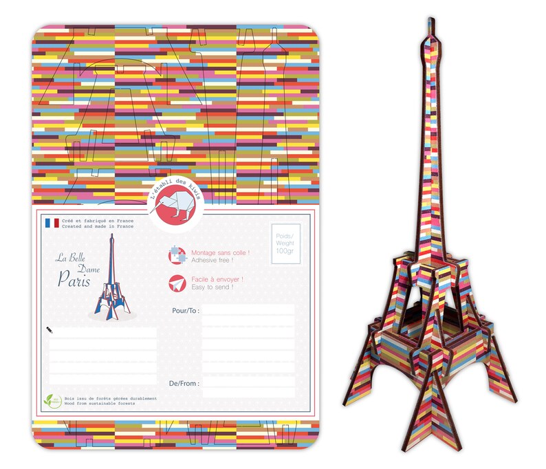 May include: A colorful, striped Eiffel Tower model postcard kit. The postcard features a space to write a message and includes the text "La Belle Dame Paris".