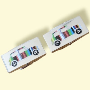 Könnte beinhalten: Ein Paar silberne Manschettenknöpfe mit einem bunten, gestreiften Mini-Auto-Design.