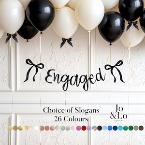 May include: A black script banner reading Engaged, flanked by two black bows, suspended below white and black balloons with black ribbon bows. Text below reads Choice of Slogans 26 Colours and Jo & Lo Designs, followed by a row of 26 coloured circles.