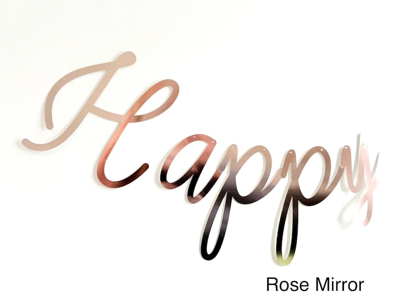Pode incluir: Faixa "Happy" com acabamento espelhado rosa. A palavra "Happy" &eacute; escrita em uma fonte cursiva. A faixa &eacute; feita de um material reflexivo e foi projetada para ser pendurada. O texto "Rose Mirror" est&aacute; na parte inferior.