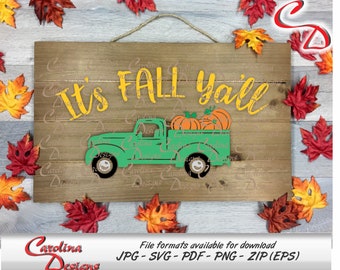 May include: A wooden sign with the text "It's Fall Y'all" in yellow lettering. A green pickup truck with a bed full of orange pumpkins is in front of the text. The sign is surrounded by fall leaves.