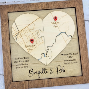 May include: Wooden heart-shaped map puzzle in a brown frame. The puzzle pieces show a map with red location markers. Text includes "The First Time Our Eyes Met" and "Where We Said I Do" with dates and names.