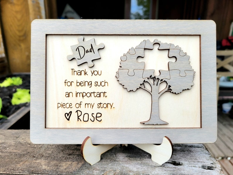 Puede incluir: Un letrero de madera con un marco gris y un dise&ntilde;o de &aacute;rbol de piezas de rompecabezas. El letrero dice "Pap&aacute; Gracias por ser una parte tan importante de mi historia. &hearts; Rosa"