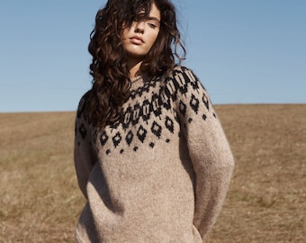 Könnte beinhalten: Ein brauner Pullover mit einem schwarzen und weißen geometrischen Muster am Ausschnitt. Der Pullover ist aus einem weichen, flauschigen Material.